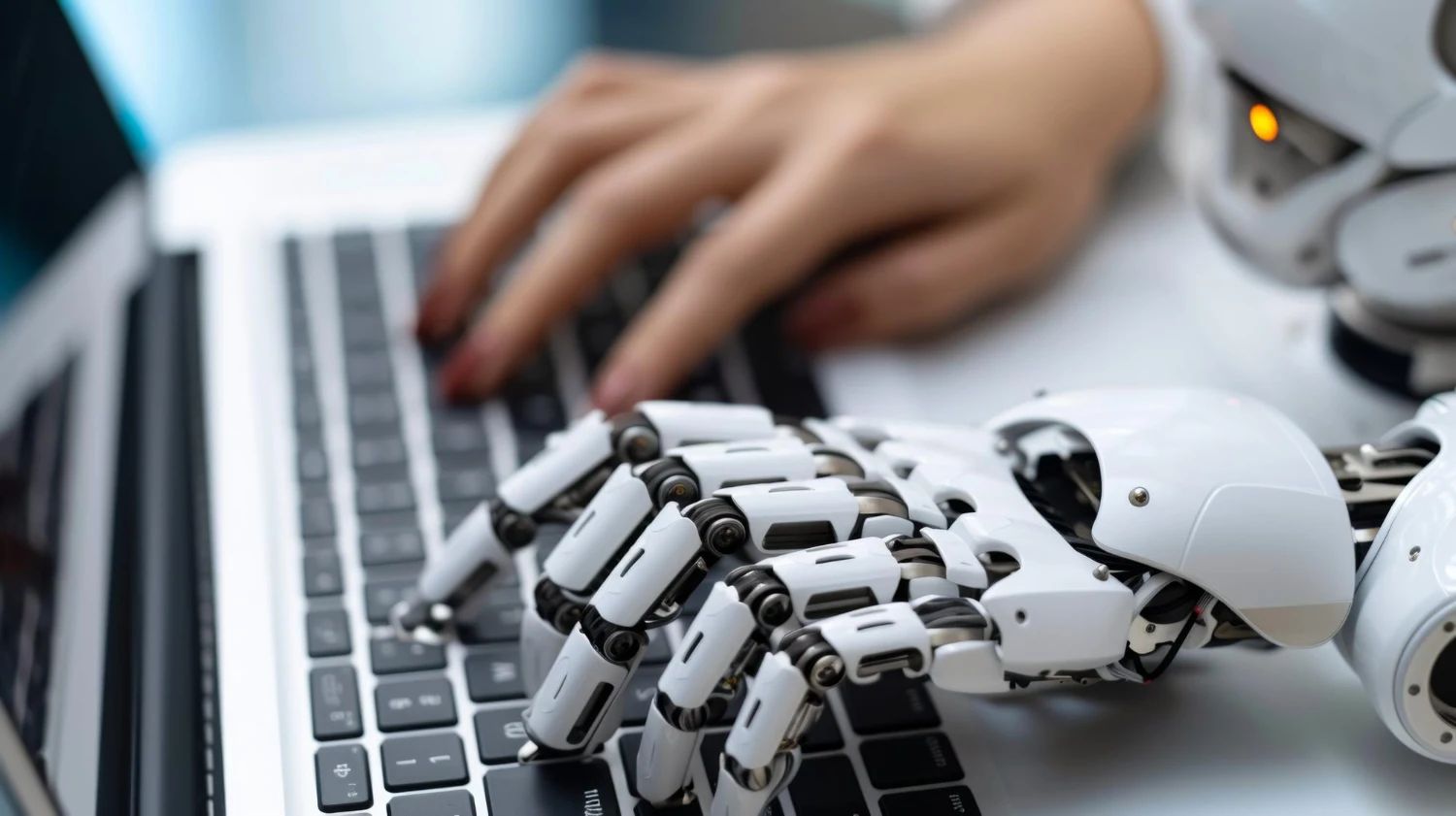 Mão humana e mão robótica digitando lado a lado em um teclado, representando colaboração entre pessoas e inteligência artificial.